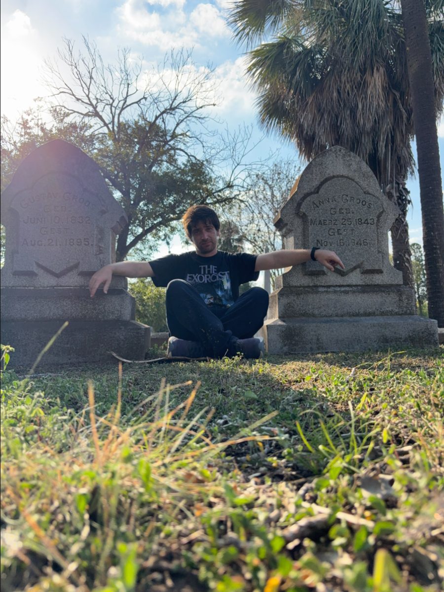 Nicolás sitting between two 19th-century headstones at Oakwood Cemetery in Austin